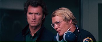 Movie still from “Magnum Force” (1973), directed by Ted Post – A man standing next to a woman wearing headphones; Close Up shot, Low angle