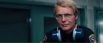 Movie still from “Magnum Force” (1973), directed by Ted Post – A police officer with glasses and headphones; Close Up shot, Over the shoulder angle