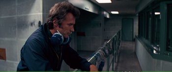 Movie still from “Magnum Force” (1973), directed by Ted Post – A man wearing headphones and a black shirt is looking at a camera; Close Up shot, Over the shoulder angle