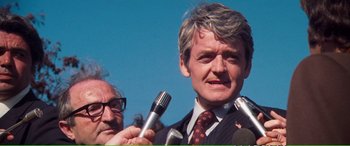 Movie still from “Magnum Force” (1973), directed by Ted Post – A man in a suit and tie holding a microphone; Close Up shot, Low angle