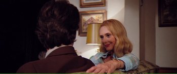 Movie still from “Magnum Force” (1973), directed by Ted Post – A woman holding a man's hand in a room with pictures on the wall; Medium shot, Over the shoulder angle