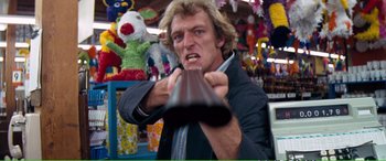 Movie still from “Magnum Force” (1973), directed by Ted Post – A man holding a chocolate bar in front of a crowd; Medium shot, Low angle