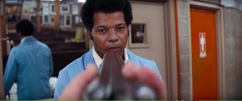 Movie still from “Magnum Force” (1973), directed by Ted Post – A man holding a bottle of wine in front of his face; Close Up shot, Low angle