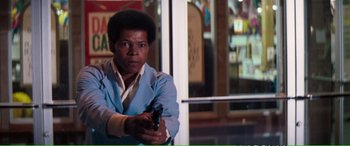 Movie still from “Magnum Force” (1973), directed by Ted Post – A man holding a gun while standing in front of a window; Medium shot, Low angle