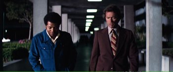 Movie still from “Magnum Force” (1973), directed by Ted Post – Two men in suits walking down a hall way; Medium shot, Low angle
