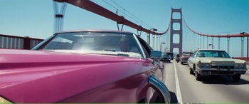 Movie still from “Magnum Force” (1973), directed by Ted Post – A man driving a pink car across a bridge; Wide shot, Low angle