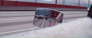 Movie still from “Magnum Force” (1973), directed by Ted Post – A rear view mirror of a motorcycle on a highway; Wide shot, Over the shoulder angle