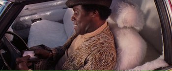 Movie still from “Magnum Force” (1973), directed by Ted Post – A person sitting on a couch wearing a hat; Medium shot, Overhead angle