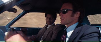Movie still from “Magnum Force” (1973), directed by Ted Post – Two men in suits and ties in the back of a car; Medium shot, Over the shoulder angle
