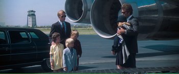 Movie still from “Magnum Force” (1973), directed by Ted Post – A group of people standing on a tarmac near an airplane; Wide shot, Over the shoulder angle