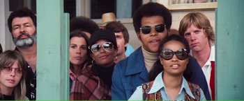 Movie still from “Magnum Force” (1973), directed by Ted Post – A group of people standing next to each other wearing sunglasses; Medium shot, Low angle