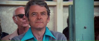 Movie still from “Magnum Force” (1973), directed by Ted Post – An older man wearing a blue shirt and a gray jacket; Close Up shot, Over the shoulder angle