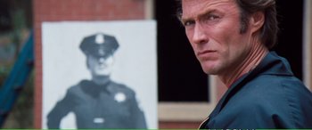 Movie still from “Magnum Force” (1973), directed by Ted Post – A man in a police uniform standing in front of a picture of a police officer; Close Up shot, Over the shoulder angle