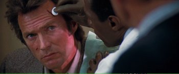 Movie still from “Magnum Force” (1973), directed by Ted Post – A man is getting his head examined by an ophthalmologist; Close Up shot, Over the shoulder angle