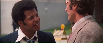 Movie still from “Magnum Force” (1973), directed by Ted Post – Two men in business suits talking to each other; Close Up shot, Over the shoulder angle