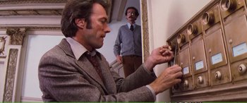 Movie still from “Magnum Force” (1973), directed by Ted Post – A man in a suit painting a picture on a wall; Medium shot, Low angle