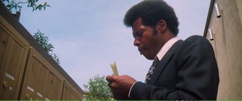 Movie still from “Magnum Force” (1973), directed by Ted Post – A man in a business suit looking down at a piece of paper; Close Up shot, Low angle