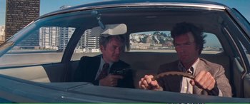 Movie still from “Magnum Force” (1973), directed by Ted Post – Two men sitting in the back seat of a car; Medium shot, Over the shoulder angle