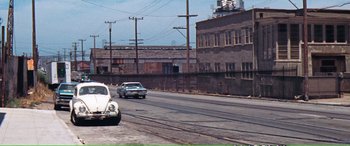 Movie still from “Magnum Force” (1973), directed by Ted Post – An old car is parked on the side of the road; Extreme Wide shot, High angle