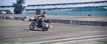 Movie still from “Magnum Force” (1973), directed by Ted Post – A man riding a motorcycle down the street; Wide shot, High angle