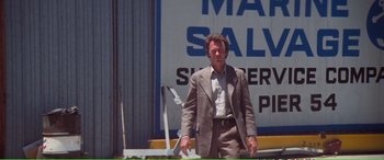 Movie still from “Magnum Force” (1973), directed by Ted Post – A man standing in front of an advertisement; Medium shot, Low angle