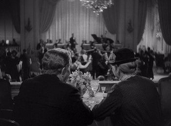 Movie still from “Make Way for Tomorrow” (1937), directed by Leo McCarey – Two people sitting at a table in front of an orchestra; Wide shot, High angle