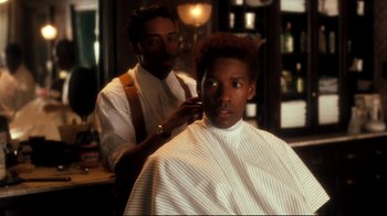 Movie still from “Malcolm X” (1992), directed by Spike Lee – A man getting his hair combed by a barber; Close Up shot, Over the shoulder angle
