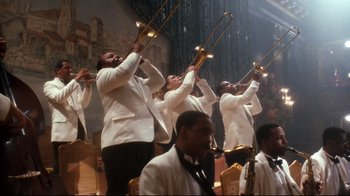 Movie still from “Malcolm X” (1992), directed by Spike Lee – A group of men in white jackets playing musical instruments; Extreme Wide shot, Low angle
