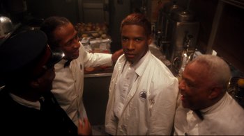Movie still from “Malcolm X” (1992), directed by Spike Lee – A group of men standing in a kitchen preparing food; Close Up shot, Over the shoulder angle