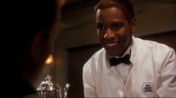 Movie still from “Malcolm X” (1992), directed by Spike Lee – A man sitting at a table in front of a tea pot; Close Up shot, Over the shoulder angle