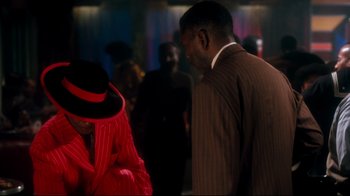 Movie still from “Malcolm X” (1992), directed by Spike Lee – A man in a suit and a woman in a red dress; Medium shot, Over the shoulder angle