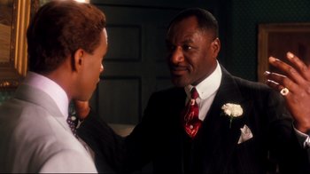 Movie still from “Malcolm X” (1992), directed by Spike Lee – A man in a suit and tie talking to another man in a suit and tie; Close Up shot, Over the shoulder angle