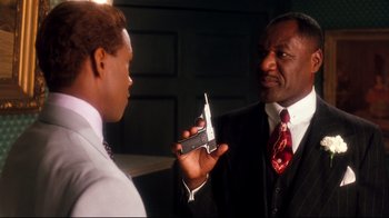 Movie still from “Malcolm X” (1992), directed by Spike Lee – A man in a suit and tie holding a cell phone in his hand; Close Up shot, Over the shoulder angle