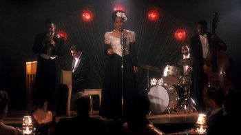 Movie still from “Malcolm X” (1992), directed by Spike Lee – A woman in a white dress singing on a stage; Wide shot, High angle
