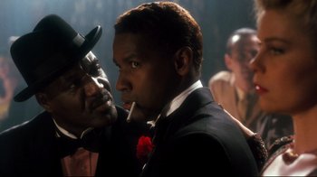 Movie still from “Malcolm X” (1992), directed by Spike Lee – A man in a black suit and a man in a red bow tie; Close Up shot, Over the shoulder angle