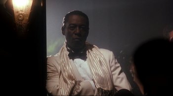 Movie still from “Malcolm X” (1992), directed by Spike Lee – A man wearing a white suit and a white tie; Close Up shot, Low angle
