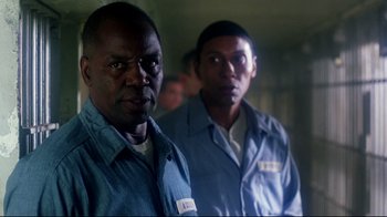 Movie still from “Malcolm X” (1992), directed by Spike Lee – A couple of men standing next to each other in a room; Close Up shot, Over the shoulder angle