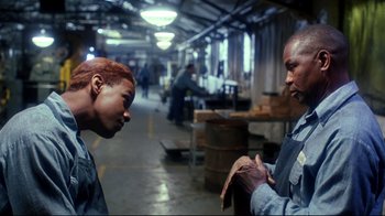 Movie still from “Malcolm X” (1992), directed by Spike Lee – Two men talking in an industrial setting; Medium shot, Over the shoulder angle