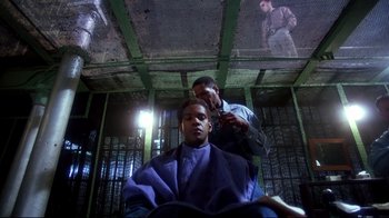 Movie still from “Malcolm X” (1992), directed by Spike Lee – A man getting his hair cut by another man; Medium shot, Low angle