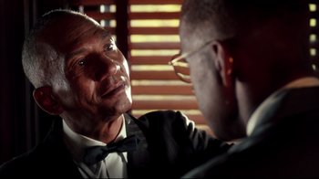 Movie still from “Malcolm X” (1992), directed by Spike Lee – A man in a suit and a bow tie is talking to another man in a suit and a bow tie; Close Up shot, Over the shoulder angle