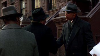 Movie still from “Malcolm X” (1992), directed by Spike Lee – Two men in suits and hats shake hands; Medium shot, Over the shoulder angle