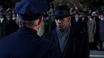 Movie still from “Malcolm X” (1992), directed by Spike Lee – A man wearing a hat and a coat talking to another man wearing a hat; Close Up shot, Over the shoulder angle