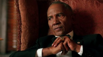 Movie still from “Malcolm X” (1992), directed by Spike Lee – An older man adjusting his bow tie while sitting in a chair; Close Up shot, Low angle