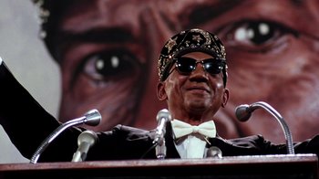 Movie still from “Malcolm X” (1992), directed by Spike Lee – An older man wearing a suit and a hat; Close Up shot, Low angle