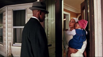 Movie still from “Malcolm X” (1992), directed by Spike Lee – A man in a suit and a hat holding a baby; Medium shot, Over the shoulder angle