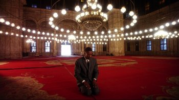 Movie still from “Malcolm X” (1992), directed by Spike Lee – A man sitting on the ground in a large room; Extreme Wide shot, High angle