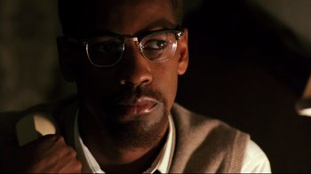 Movie still from “Malcolm X” (1992), directed by Spike Lee – A person wearing glasses; Close Up shot, Over the shoulder angle