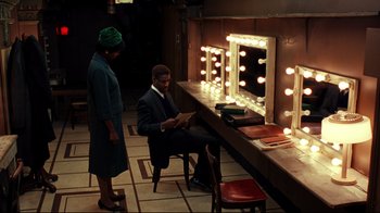 Movie still from “Malcolm X” (1992), directed by Spike Lee – A man and a woman in front of a lighted mirror; Wide shot, High angle