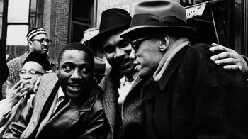 Movie still from “Malcolm X” (1992), directed by Spike Lee – A black - and - white photo of a group of men standing next to each other; Medium shot, High angle