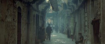 Movie still from “Malena” (2000), directed by Giuseppe Tornatore – A group of people walking down a narrow street; Wide shot, High angle